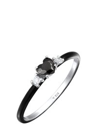 Anillo de gema negra en forma de corazón con dos acentos redondos claros, montado en una banda de plata pulida, marcado con "925" que indica plata esterlina.