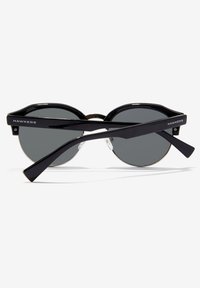 Ochelari de soare Black Hawkers cu lentile rotunde întunecate și brațe negre, încrucișate în față pe un fundal alb.