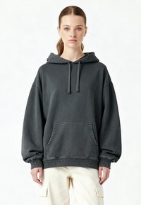 Felpa con cappuccio oversize grigia realizzata in morbido cotone, dotata di tasca frontale, cappuccio con laccetti e polsini a costine. Design casual con una vestibilità rilassata.