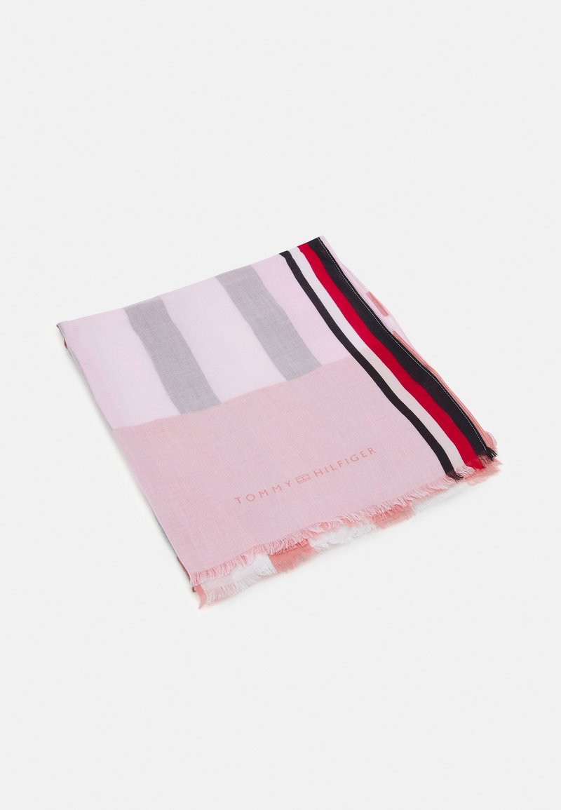Écharpe rose pliée Tommy Hilfiger avec des rayures grises, blanches, rouges et noires ainsi que des bords à franges sur fond blanc.