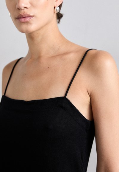 Black sleeveless top with thin straps, featuring a straight neckline and smooth texture, highlighting the collarbone and shoulder area.