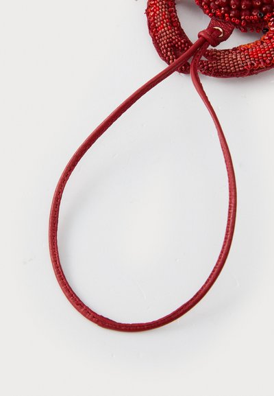 Röd pärlarmband med ett flätat läderband. Pärlorna har varierande texturer och nyanser, vilket ger ett lager-på-lager utseende.