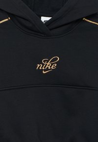 Hanorac negru cu buzunar frontal, având un logo "nike" brodat cu fir auriu și un material texturat. Include o glugă cu șnur.