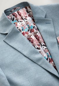 Lyseblå tekstureret blazer med foring i blomsterprint i pink, teal og hvid. Har en notch krave og en skræddersyet pasform.