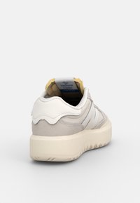 Baskets beige clair et blanc avec semelle épaisse, détails en daim et mesh, vues de dos sur fond blanc.