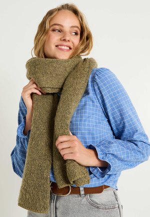 Bufanda de punto verde oliva, textura suave, acabado ligeramente difuso, se drapea libremente alrededor del cuello, se sujeta de manera segura, combinada con una camisa a cuadros azul.