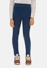 Leggings elásticos azul marino con una textura suave y cintura alta, combinados con zapatillas multicolores que tienen cordones y una suela acolchada.