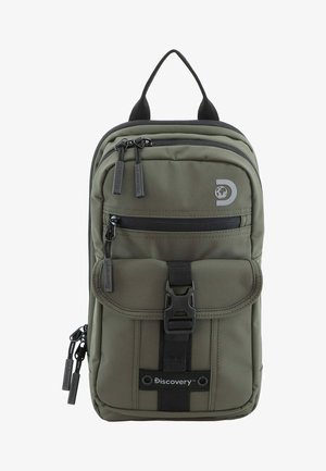 Mochila de color verde oliva con un compartimento principal con cremallera, un bolsillo con solapa en la parte delantera y detalles en negro. Cuenta con cremalleras dobles y un asa de transporte en la parte superior.