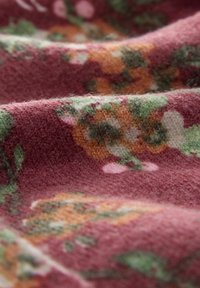 Tissu à motifs floraux dans des tons de rose foncé, de vert atténué et d'orange ; texture douce avec une surface duveteuse. Motif floral détaillé sur l'ensemble.