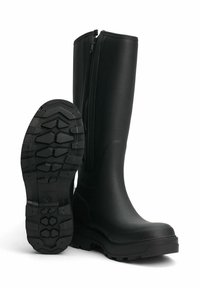 Bottes en caoutchouc noires imperméables au design haut, avec une fermeture éclair sur le côté et une semelle en caoutchouc texturée dotée d'un motif de grip hexagonal.