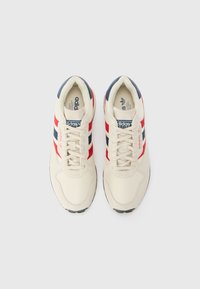 Beige lærreds sneakers med røde og marineblå striber, rund tå og snørebåndsdesign. Inkluderer en polstret krave og tekstureret gummisål.
