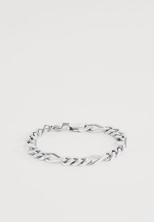 Bracelet chaîne en argent avec des maillons torsadés et plats alternés et un fermoir griffe de homard sur un fond clair uni.