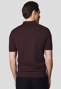 Burgundowa koszulka polo z krótkim rękawem, z ribbowanym kołnierzykiem i dołem. Gładka dzianinowa tekstura, dopasowany krój i brak widocznych zdobień.