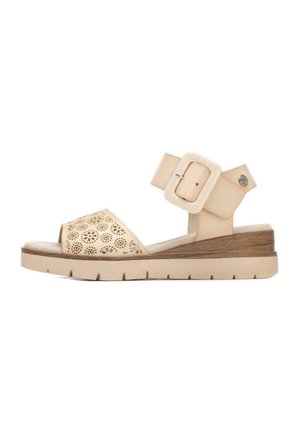 Sandalia beige de punta abierta con patrones florales cortados con láser, correa ajustable en el tobillo con hebilla grande y suela gruesa de goma con ligero tacón.