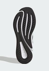 Suela de zapatilla en blanco y negro con bandas texturizadas y surcos pronunciados; diseñada para ofrecer agarre y durabilidad. Acentuada con líneas suaves.