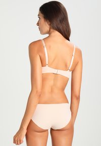 Beige bikinitopp som har et glatt, minimalistisk design. Toppen har justerbare stropper og en krokfeste, mens bunnen har en enkel, lavt skåret stil.