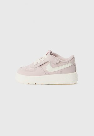 Roze leren sneakers met een witte swoosh, platte veters, een gevoerde kraag, een gestructureerde zool en een klein logo op de hiel en zijkant.
