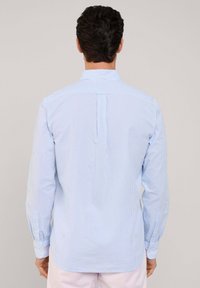 Camicia a maniche lunghe blu e bianca a righe con colletto e patta dei bottoni, dotata di piega sul retro, tessuto di cotone, texture liscia.