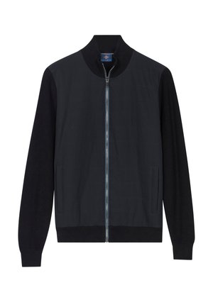 Zwarte jas met volledige ritssluiting, voorzien van een geribbelde kraag, manchetten en zoom, met twee voorzakken en een subtiel gestructureerd patroon op het lijf.