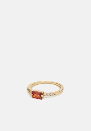 Gold ring featuring a rectangular red gemstone at the center, flanked by small sparkling stones along the band. Smooth, polished finish.