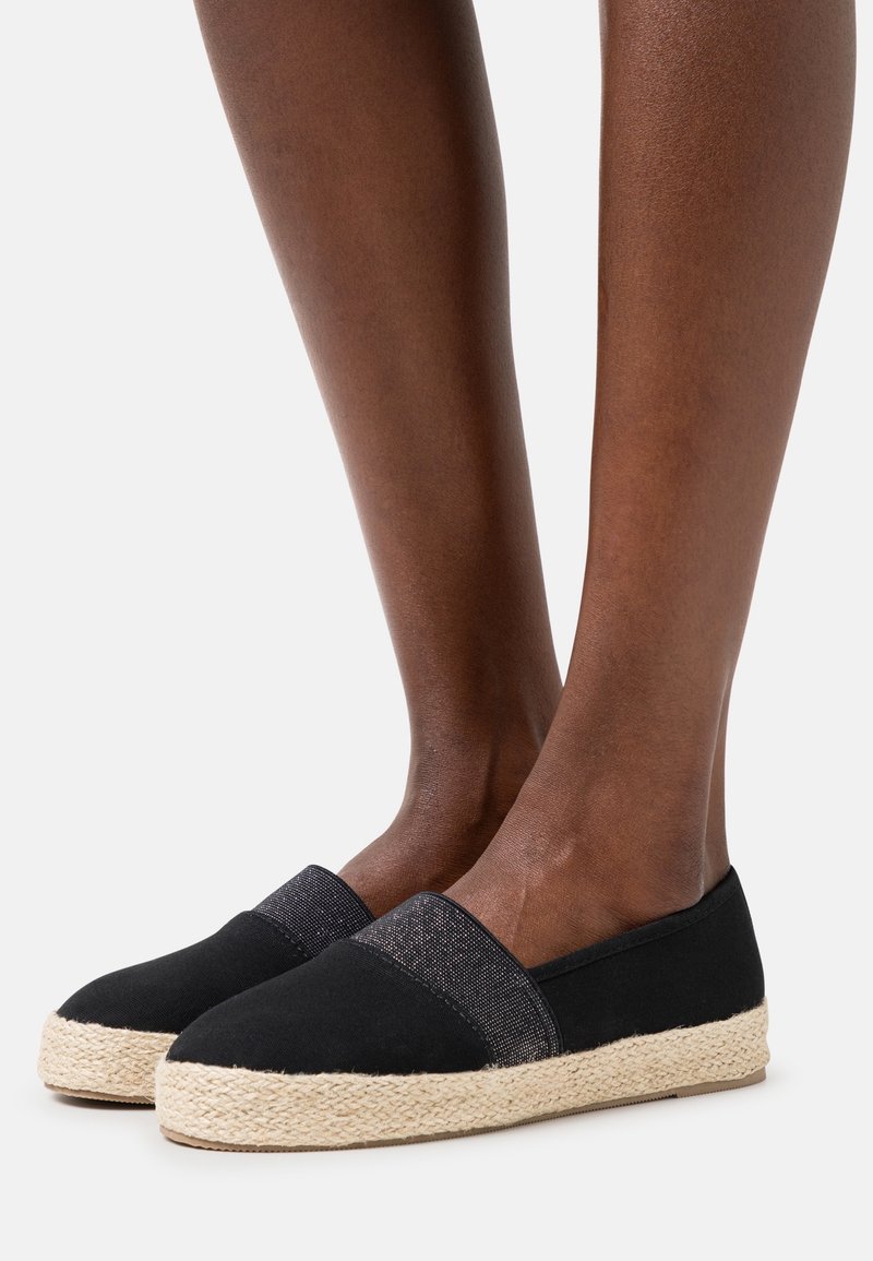 Espadrilles de lona negra con una banda elástica texturizada negra. La suela de cuerda de yute añade un elemento natural al diseño. Silueta de perfil bajo.
