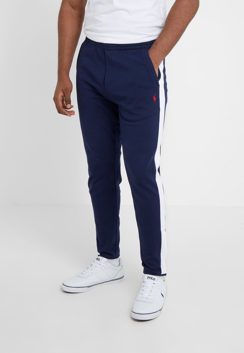 Marina joggerbyxor med vita sidstripe, elastisk midja och logobroderi. Stylad med vita sneakers.