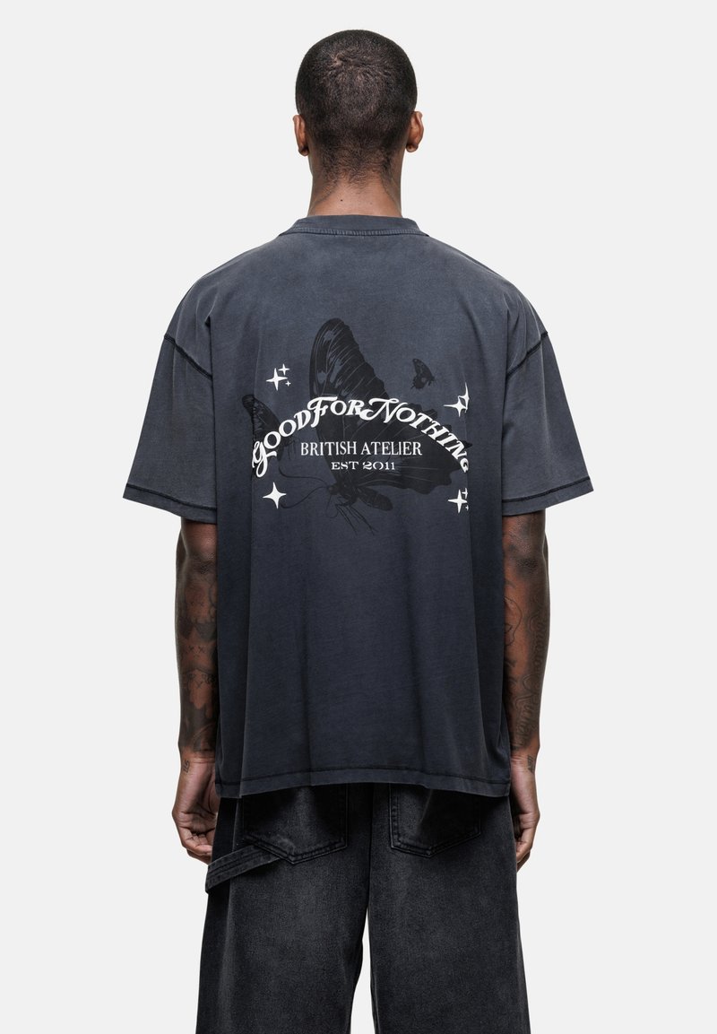 Czarnoszary, oversized T-shirt z graficznym motywem motyla i napisem, z okrągłym dekoltem i krótkimi rękawami. Materiał bawełniany o przetartym wyglądzie.