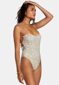 Floral one-piece swimsuit in light blue, featuring orange and white flower patterns, thin straps, and cut-out sides for a sleek fit.
