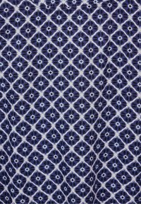 Tessuto con un motivo geometrico a diamante blu e bianco, caratterizzato da una finitura texturizzata. Il design include varie sfumature di blu e accenti neri.
