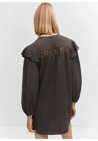 Robe gris foncé à coupe décontractée, avec des manches volantées et une insertion en dentelle dans le dos. Confectionnée dans un tissu texturé et léger.