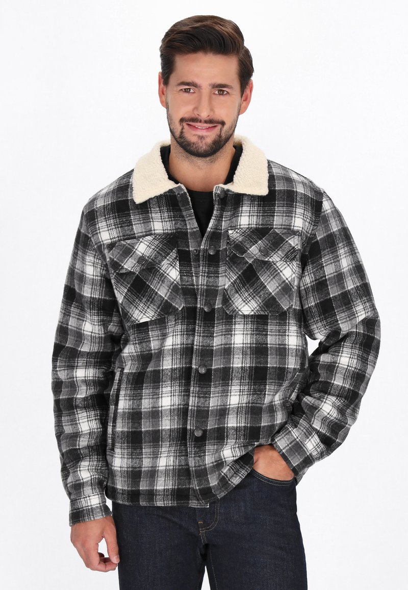 Czarna i biała koszula w kratę flanelowa z miękkim beżowym kołnierzem sherpa, zatrzaskami i dwoma kieszeniami na piersi. Gładki, teksturowany materiał.
