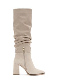 Beżowe, sztuczne zamszowe kozaki za kolano o luźnym kroju, ze złotym zapięciem na zamek i 4-calowym słupkowym obcasie. O kształcie spiczastego nosa.