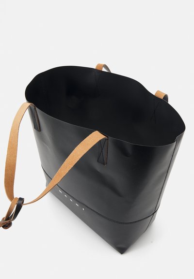 Borsa tote in pelle nera con manici in pelle marrone, caratterizzata da un bordo superiore curvo, design semplice e dettagli di cucitura a contrasto alla base.