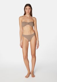 Bikini-set in ribbelstof, beige. Kenmerkt zich door een strapless top met een strikdetail en een high-waisted onderstuk. Gladde textuur en minimaal ontwerp.