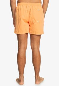 Oranje zwemshorts gemaakt van lichtgewicht stof, met een elastische tailleband, achterzak en een eenvoudig ontwerp.