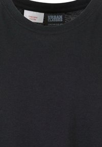 Svart bomulls T-shirt med rund halsringning. Tyget verkar slätt och något strukturert, med en skötseltyp som finns inuti.