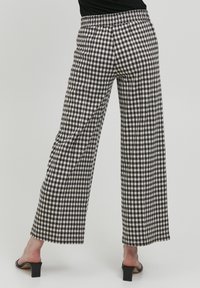 Pantalons large à carreaux noir et blanc avec une taille élastique, fabriqués dans un tissu léger, présentant un ourlet propre et une coupe décontractée.