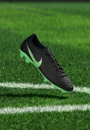 Sort og grøn Nike fodboldstøvle svæver over hvide linjer på en grøn græsmark.