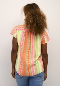 Top a maniche corte, multicolore, con motivi geometrici in rosa, arancione e verde. Tessuto leggero con vestibilità ampia e orlo curvato.