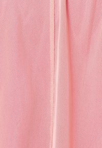 Tessuto a rete di colore rosa chiaro, caratterizzato da un motivo testurizzato traspirante. Le cuciture decorano verticalmente, migliorando il design complessivo.