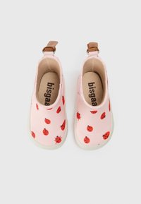 Chaussures imperméables roses avec un design à enfiler, arborant des motifs de coccinelle rouges, des accents beige et une semelle en caoutchouc blanc texturé.