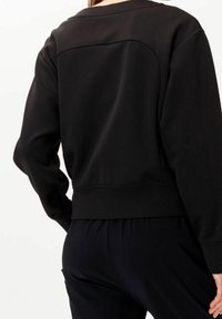 Felpa nera con cucitura a yoke arrotondata e polsini a coste, dal fit rilassato e una texture morbida, vista da dietro.