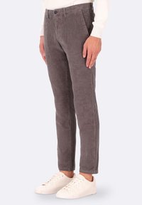 Pantaloni in corduroy di colore grigio ardesia, con trama a costine verticali, design aderente e tasche frontali standard. Abbinati a sneakers bianche.