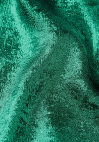 Groen fluwelen stof met een zachte, gestructureerde oppervlakte, met een rijke, diepe kleur en subtiele variaties in tinten over het materiaal.