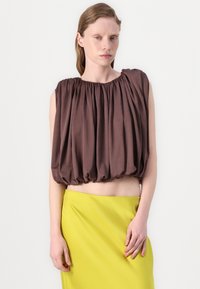 Brown puff-sleeve top with gathered fabric at the neckline, paired with a fitted lime green skirt, showcasing a smooth texture and modern silhouette.