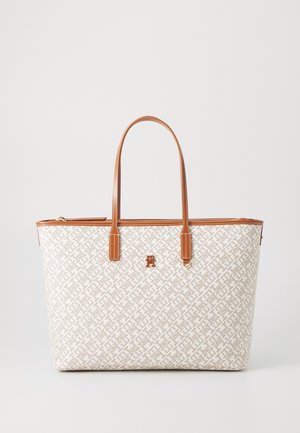 Sac cabas beige et blanc à motifs avec poignées et garniture en cuir marron, doté d'un petit logo métallique au centre devant.