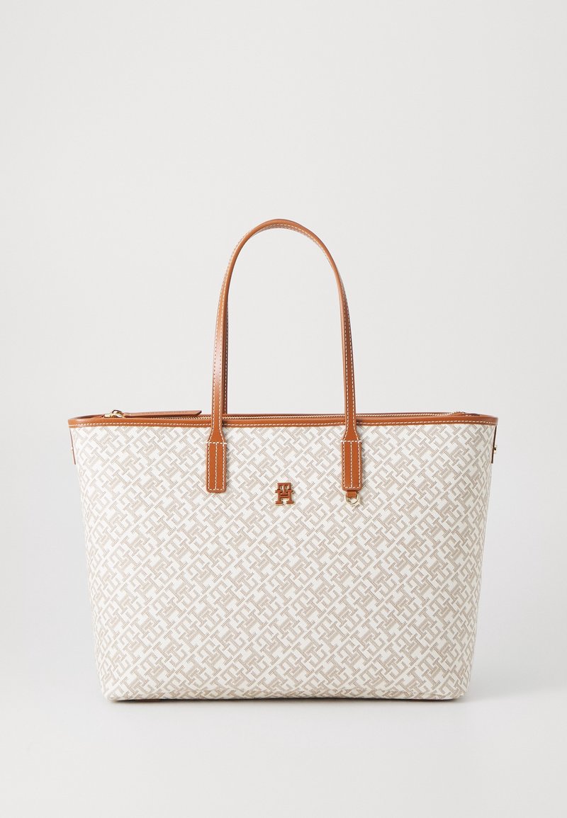 Sac cabas beige et blanc à motifs avec poignées et garniture en cuir marron, doté d'un petit logo métallique au centre devant.