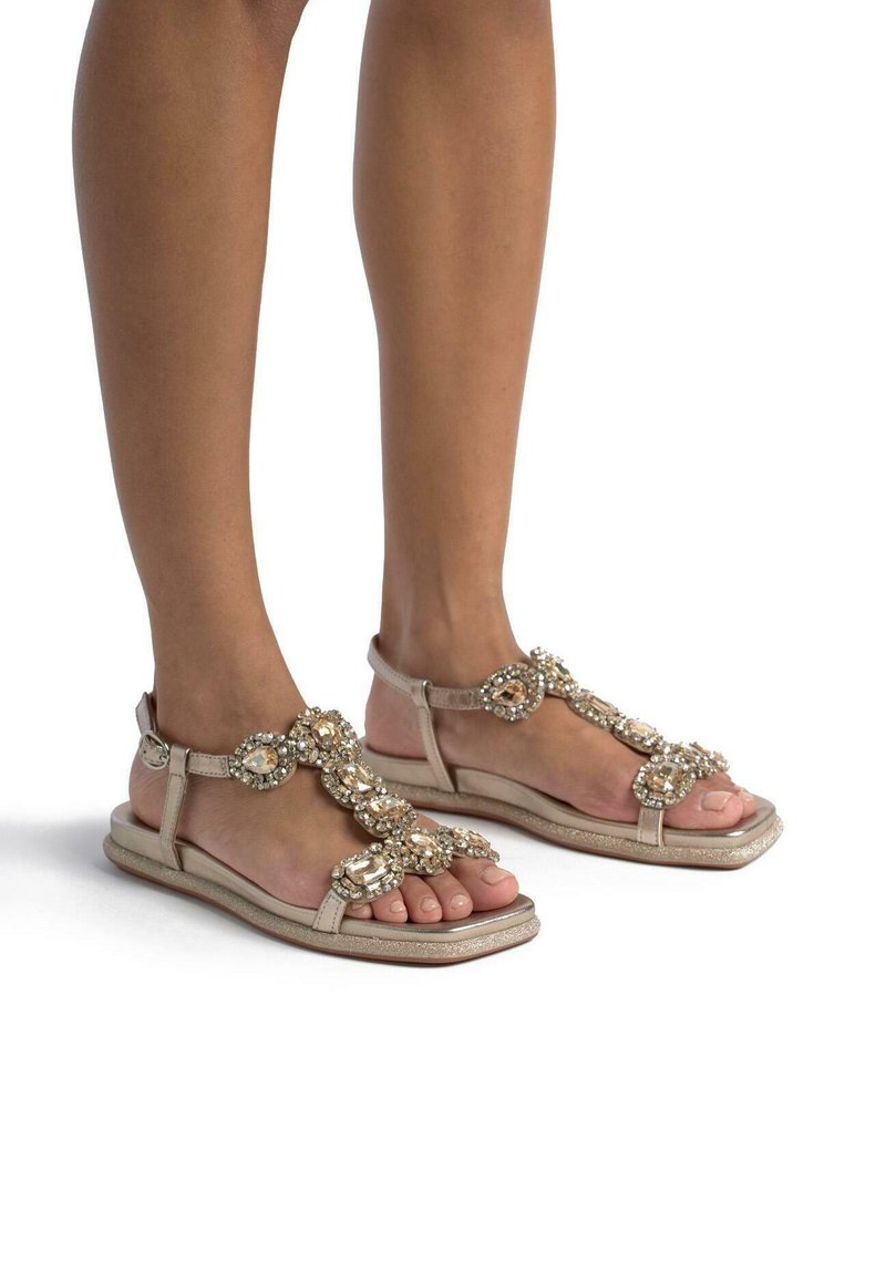 Beige platte sandalen met decoratieve strassaccenten, met een bandjesdesign en een open teenstijl. Glad leren materiaal.