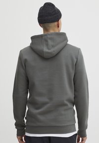 Gray hooded sweatshirt with a smooth texture, ribbed cuffs, and hem. Features a kangaroo pocket and a simple, casual design.