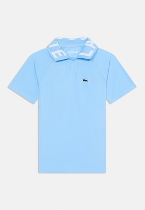 Polo azul claro com colarinho canelado apresentando o texto "LACOSTE" em branco. Pequeno logo de crocodilo verde no lado esquerdo do peito.
